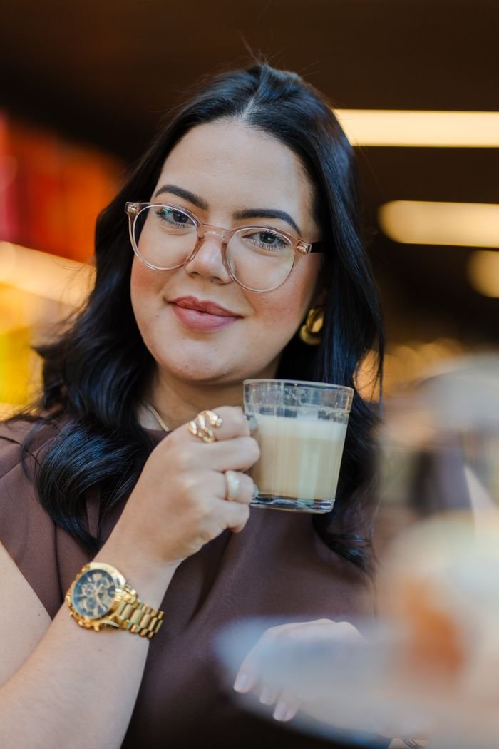 A woman elegantly holding a coffee cup indoors, exuding warmth and style with fashionable accessories
