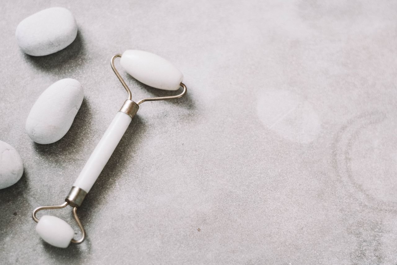 A jade roller and stones on a soft neutral background, ideal for skincare themes.